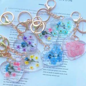 Detail of heart-shaped resin keychains with real dried flowers and gold keyrings.