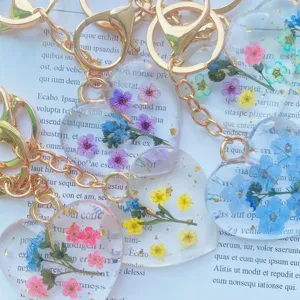 Close-up view of handmade resin keychains with colorful dried flowers and gold leaf accents