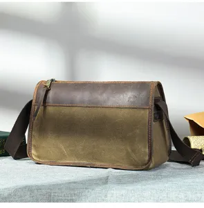 Vue détaillée du sac messager vintage en toile et cuir, tissu texturé et coutures.