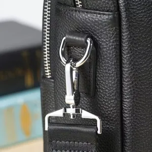 Primo piano dettaglio di ferramenta metallica borsa uomo pelle vera trama nera elegante.