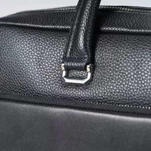 Primo piano dei dettagli di ferramenta e manico in vera pelle di borsa da lavoro.