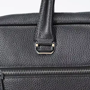 Dettaglio borsa ventiquattrore in pelle nera, pregiata texture martellata, accessori metallici.