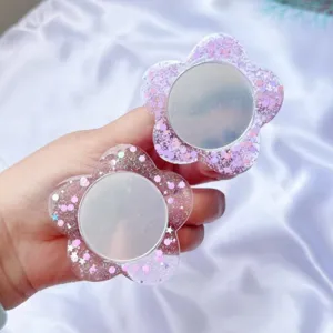 Detail eines blumenförmigen Handy-Griffs mit glitzerndem Acryl und kleinem Spiegel