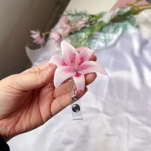 Primer plano de un porta credencial retráctil con forma de flor de lirio de acrílico rosa.