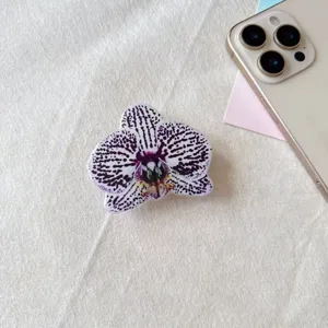 Vista detallada de un soporte para móvil con diseño de orquídea sobre fondo de tela