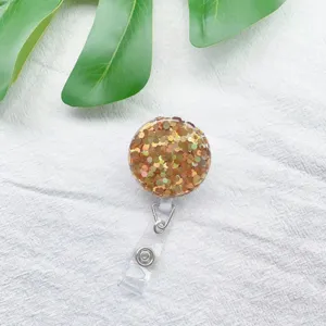 Detailansicht eines ausziehbaren Ausweishalters mit goldenem Glitzer auf Leinenhintergrund.