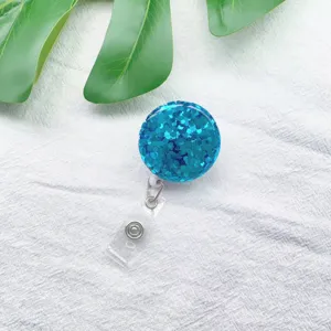Nahaufnahme eines blauen Glitzer-Ausweis Halters auf weißem Stoff mit grünen Blättern