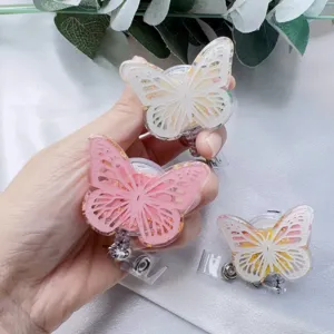 Close-up of butterfly resin badge reels with gold foil and metal alligator clips holder