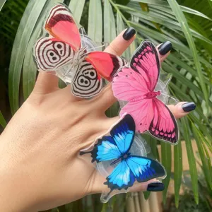 Detailed view of colorful acrylic butterfly folding phone grips held in hand