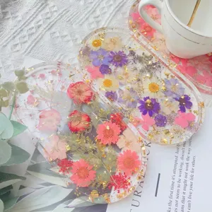 Detail van echte gedroogde bloemen en goudfolie in een transparante dienblad van hars