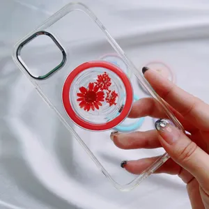 Detail showing a MagSafe phone grip with real red dried flowers on a transparent case
