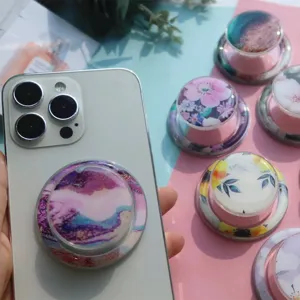 Detailed view of floral and marble resin phone grip stands on a smartphone.
