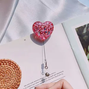 Close-up of pink glitter heart retractable badge holder on magazine background page