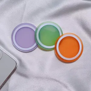 Primer plano de tres anillos magnéticos MagSafe de colores sobre tela de seda blanca