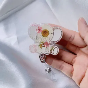 Dettaglio di un porta badge a forma di elefante con veri fiori secchi incapsulati in resina.