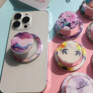 Macro view of various floral and marble epoxy magnetic phone grips on a white smartphone.