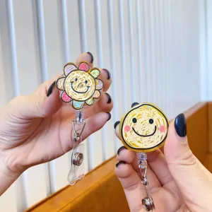 Detail view of two hand-held retractable badge holders with cute sun and flower smiley face designs.
