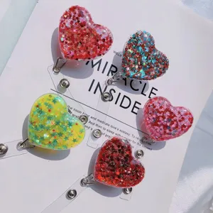 Close-up of heart-shaped glitter retractable badge reels in multiple colors.