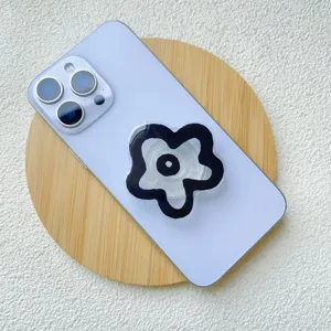 Cute acrylic flower phone socket grip stand attached to a purple smartphone back