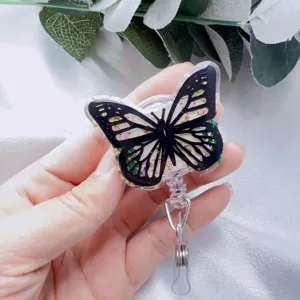 Hand holding butterfly retractable badge holder with real flowers and gold foil