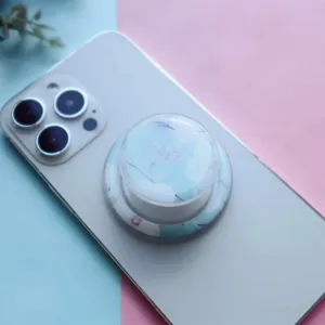 Detailed view of a floral resin air-cushion phone grip on a white smartphone