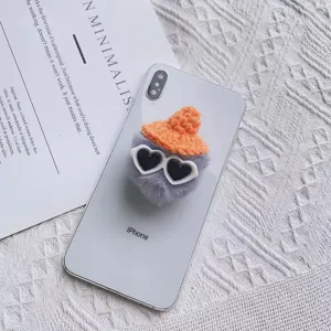 Gedetailleerd overzicht van pluche telefoonhouder met oranje gebreide muts en hartjeszonnebril