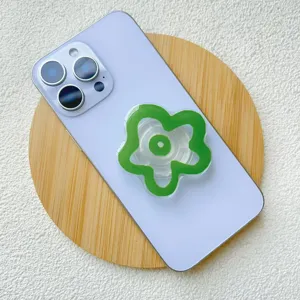 Close-up of green flower-shaped acrylic phone grip on light purple smartphone back