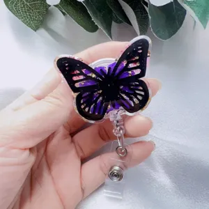 Close-up detail of butterfly resin badge reel with purple dried flowers and gold foil.