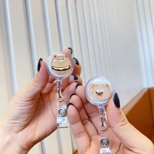 Close-up of cute glitter bear retractable badge reels held in hand