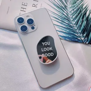 Primer plano de un soporte de espejo ovalado para móvil con texto 'YOU LOOK GOOD'