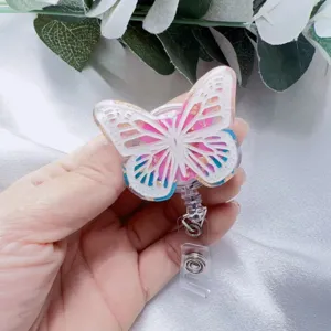 Detailed macro view of resin butterfly badge reel featuring gold foil and pink dried flowers