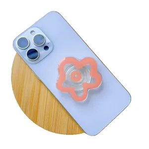 Pink flower shaped acrylic phone grip socket stand mounted on light blue smartphone