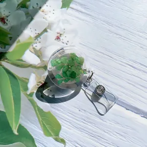 Detail of retractable badge reel featuring real dried green leaves in clear resin.