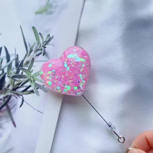 Nahaufnahme einer rosa herzförmigen, ausziehbaren Ausweishülle mit glitzernden Pailletten