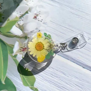 Detailed close-up of a clear resin retractable badge reel with real dried yellow flowers