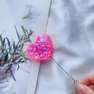 Detail eines pink glitzernden herzförmigen ausziehbaren Ausweishalters mit Kordelzug.