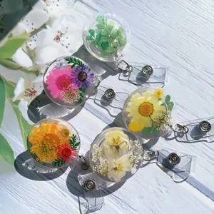Close-up of clear resin badge reels with embedded real dried flowers in natural sunlight