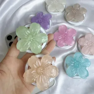 Glitzernde Handy-Halterungen in Blumenform in verschiedenen Farben auf Seidenhintergrund