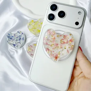 Detailed close-up of a heart-shaped resin phone grip featuring real dried flowers