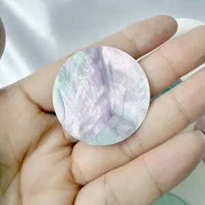 Gros plan d'une pièce ronde en nacre naturelle irisée pour la création de bijoux DIY