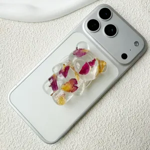 Dettaglio ravvicinato dell'impugnatura orso 3D con veri fiori secchi su smartphone argento