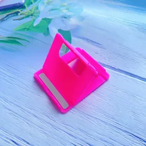 Macro view of neon pink foldable desktop stand for phones and tablets on blue background