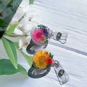 Detail view of two clear resin badge reels with vibrant real dried flowers inside