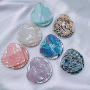Collection of heart-shaped phone grips with iridescent shell patterns on silk background