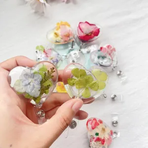 Nahaufnahme herzförmiger ausziehbarer Ausweishalter mit echten Trockenblumen und Klee