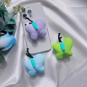 Detalle de soportes de peluche para móvil con forma de mariposa en fondo de satén blanco