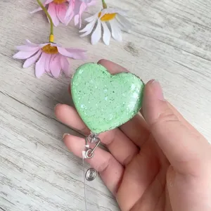 Nahaufnahme eines mintgrünen, herzförmigen, glitzernden, ausziehbaren Ausweises