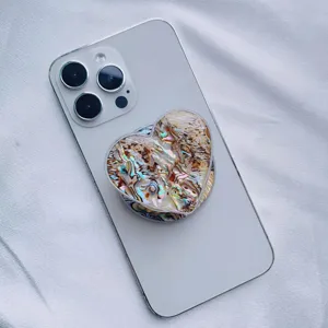 Close-up of a heart-shaped phone grip featuring natural iridescent abalone shell texture