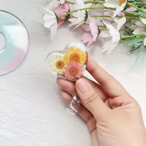 Nahaufnahme des herzförmigen Ausweis-Jojos mit echten bunten Trockenblumen im Harz.