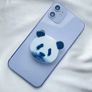Close-up detail of a cute panda face acrylic phone grip attached to a light purple smartphone